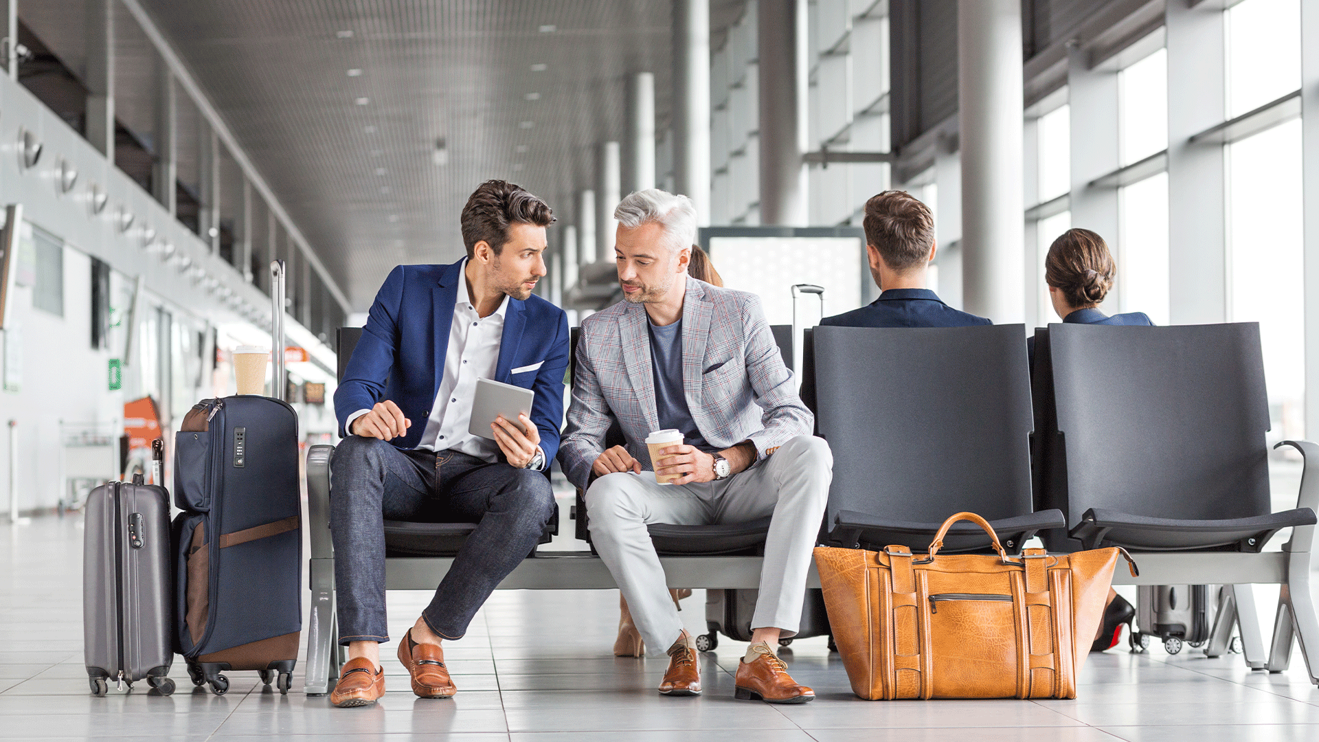 Deux voyageurs d'affaires assis dans le hall d'un aéroport avec leurs bagages