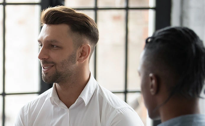 Des collègues de bureaux (deux hommes) discutant assis près d'une fenêtre