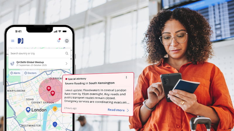 Une femme en voyage d'affaires consulte une notification sur son téléphone provenant de l'application International SOS